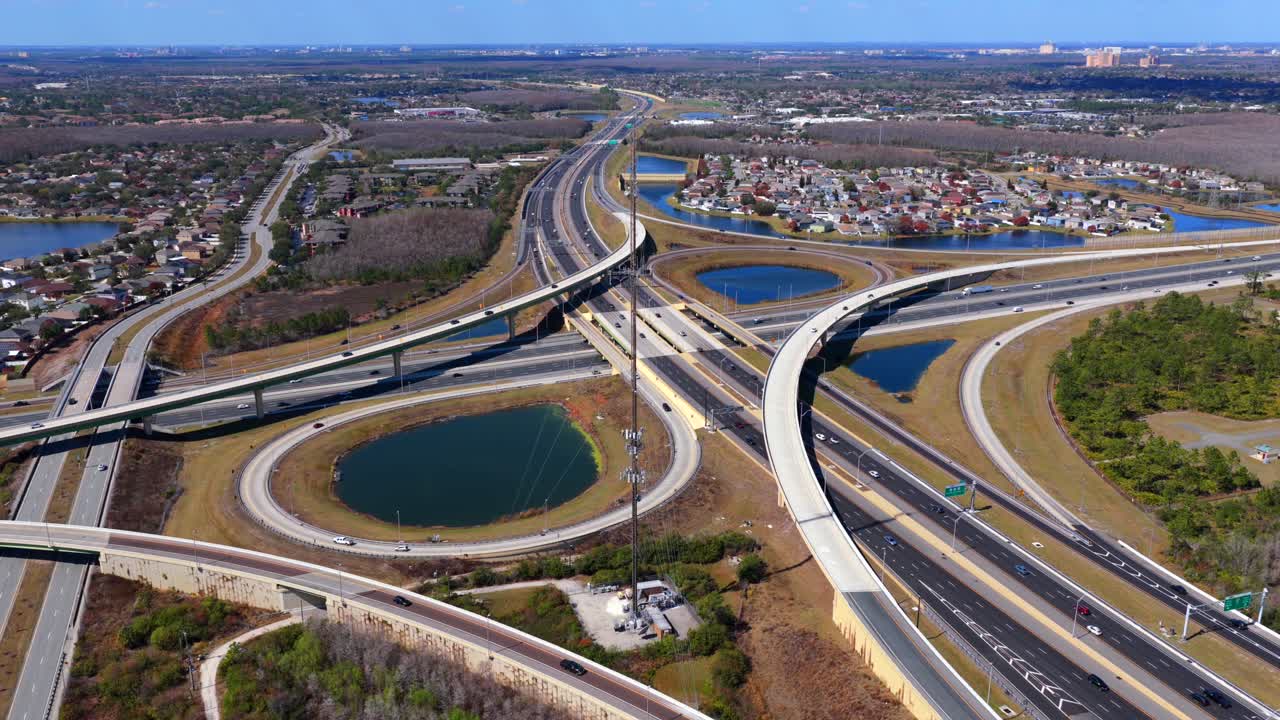 An aerial view of a large stack interchange on Florida's Turnpike on a sunny day. The camera tilted downward, truck right and pan left over the highway intersection and bodies of water