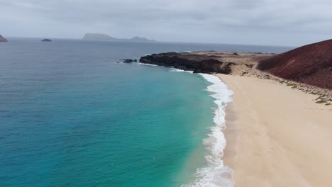 Isla-La-Graciosa:-Vista-Aérea-Viajando-A-Lo-Largo-De-La-Orilla-De-La-Playa-De-Las-Conchas-En-Un-Día-Soleado-Y-Aguas-Turquesas