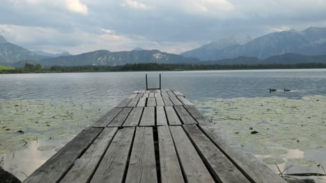 wooden jetty at lake hopfensee near fuessen with mountains in the background, bavaria, germany