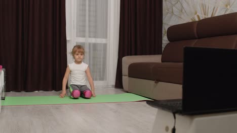 Niña-Viendo-Lecciones-A-Distancia-En-Línea-Con-Un-Entrenador-En-Una-Computadora-Portátil,-Haciendo-Ejercicio-Con-Hilo-En-Casa