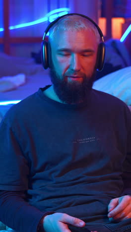 man listening to music with headphones in a dimly lit room