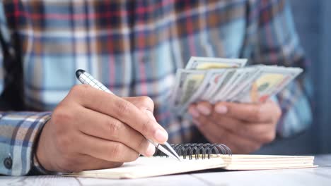 person writing notes with money