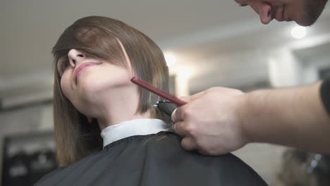 Close-Up-view-of-a-hairdresser's-hands-cutting-hair-with-scissors.-Hairdresser-at-work.-Beauty-salon.-shot-in-Slow-Motion