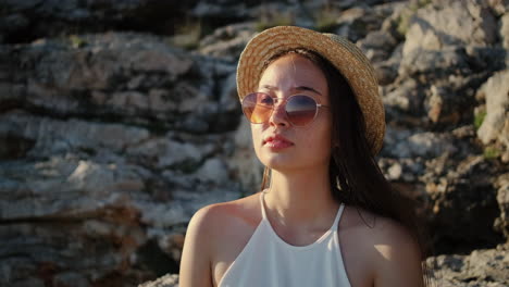 mujer con sombrero de paja y gafas de sol por las rocas