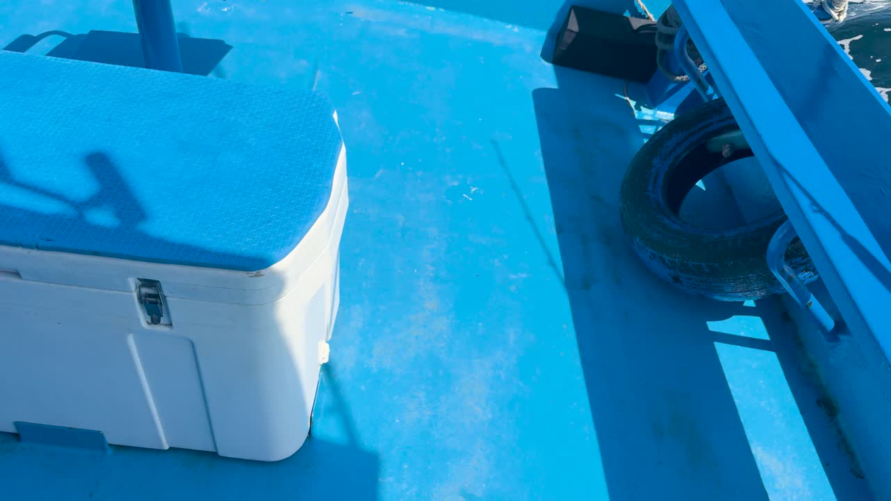 A boat gently sways on bright blue waters in Phuket, Thailand. The video captures the serene marine environment with vivid colors