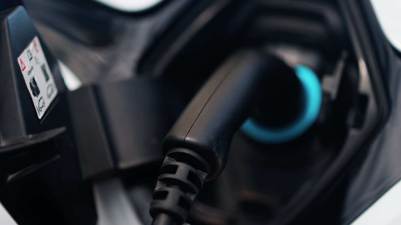 Close up of an electric car charger plugged into a white car