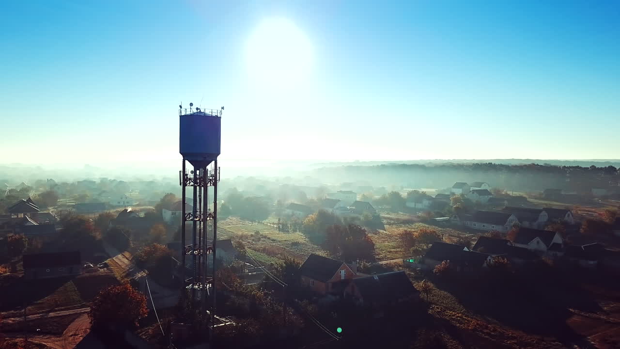 Dron shot aerial over the countryside and the big steel tower at sunrise. High metal construction in the rural place in the morning dawn. Camera moves left.