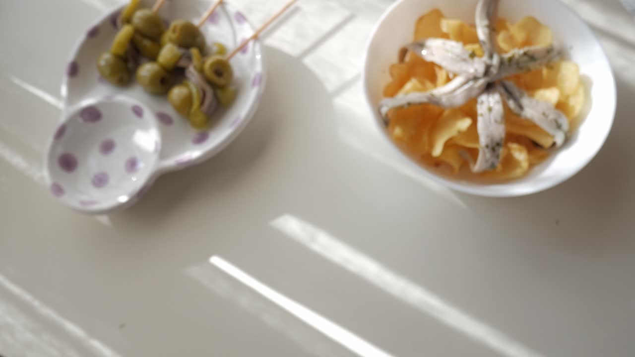 Delicious Spanish tapas with green olives and crispy chips topped with anchovies