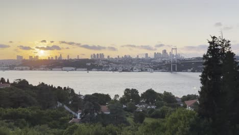 istanbul bosphorus bridge at sunset, sun drops slowly behind turkish skyline