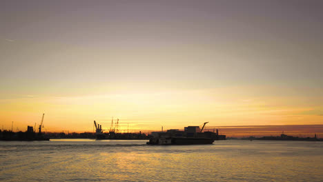 Golden-sunset-of-the-harbour-of-Rotterdam,-ship-passing-by