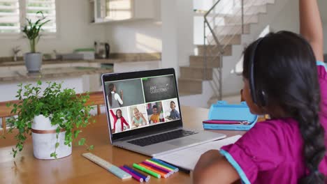 Schoolgirl-using-laptop-for-online-lesson-at-home,-with-diverse-teacher-and-class-on-screen