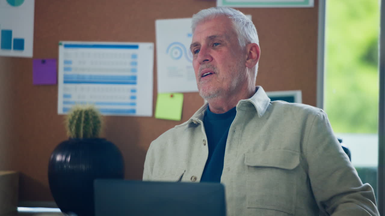 Senior Man Talking and Gesturing During a Business Meeting in an Office