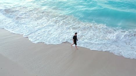 young male walking along a sandy beach in providenciales at sunset in the turks and caicos archipelago