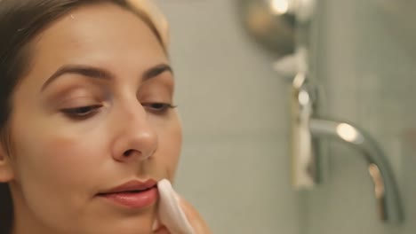 mujer aplicando removedor de maquillaje en el baño