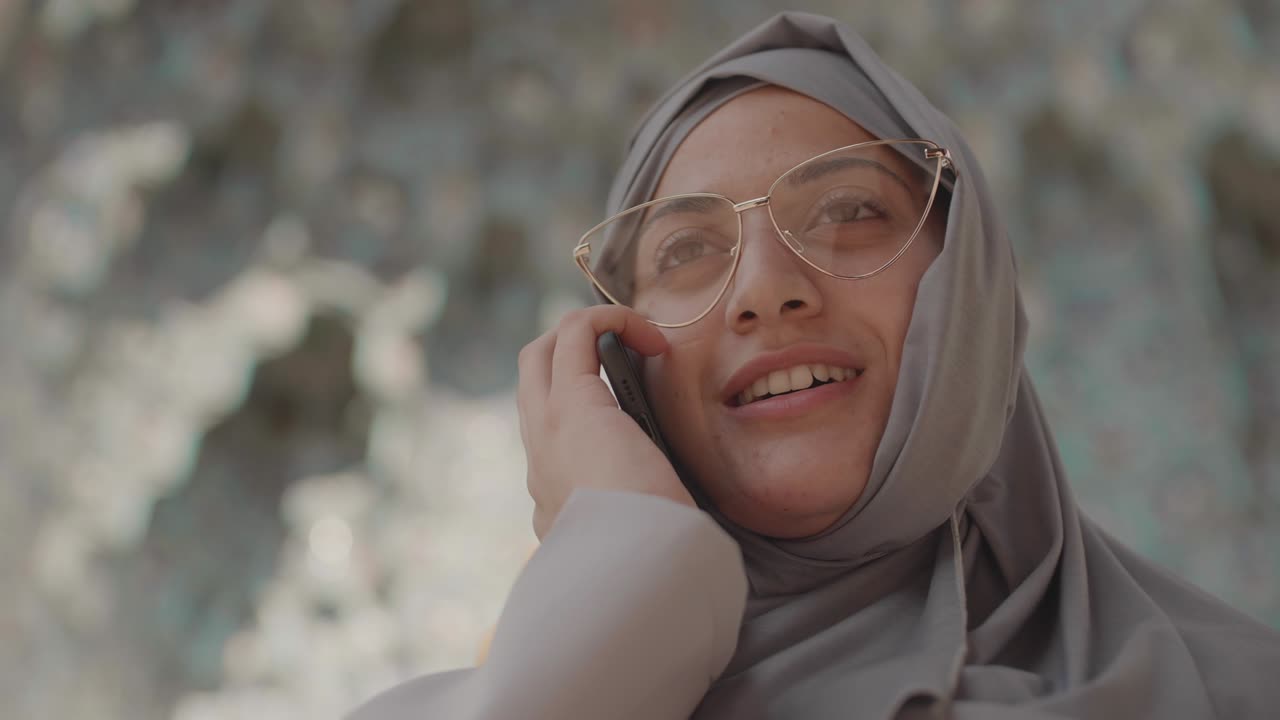 아름다운 이슬람 여성이 전화 채팅을 하고 있습니다.