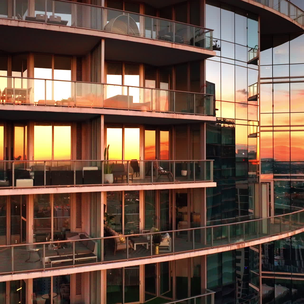 Golden light of sunset reflecting in the mirror windows of apartment block. Modern residential building in Miami, United States.