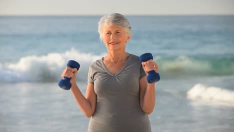 mujer de edad trabajando sus músculos con pesas