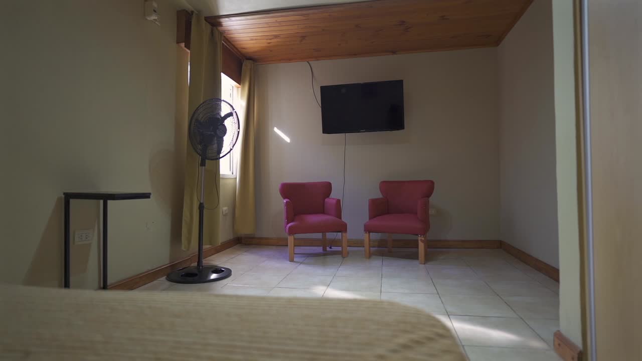 Minimalist house bedroom with two red chairs under wooden ceiling and natural light.
