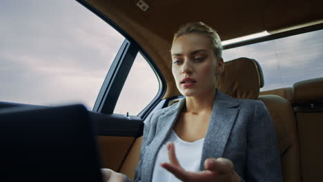 Angry businesswoman having video call at car. Confident woman using computer