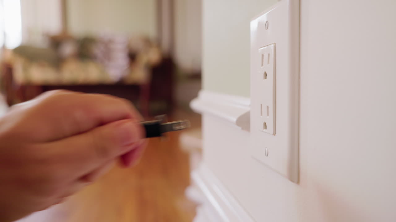 Hand inserting and removing American electrical plug from wall outlet