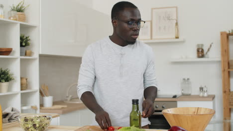 hombre afroamericano cocinando ensalada de verduras en la cocina