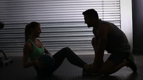 Fit-woman-doing-weighted-sit-up-with-trainer