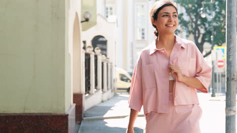 smiling woman in pink outfit on city street