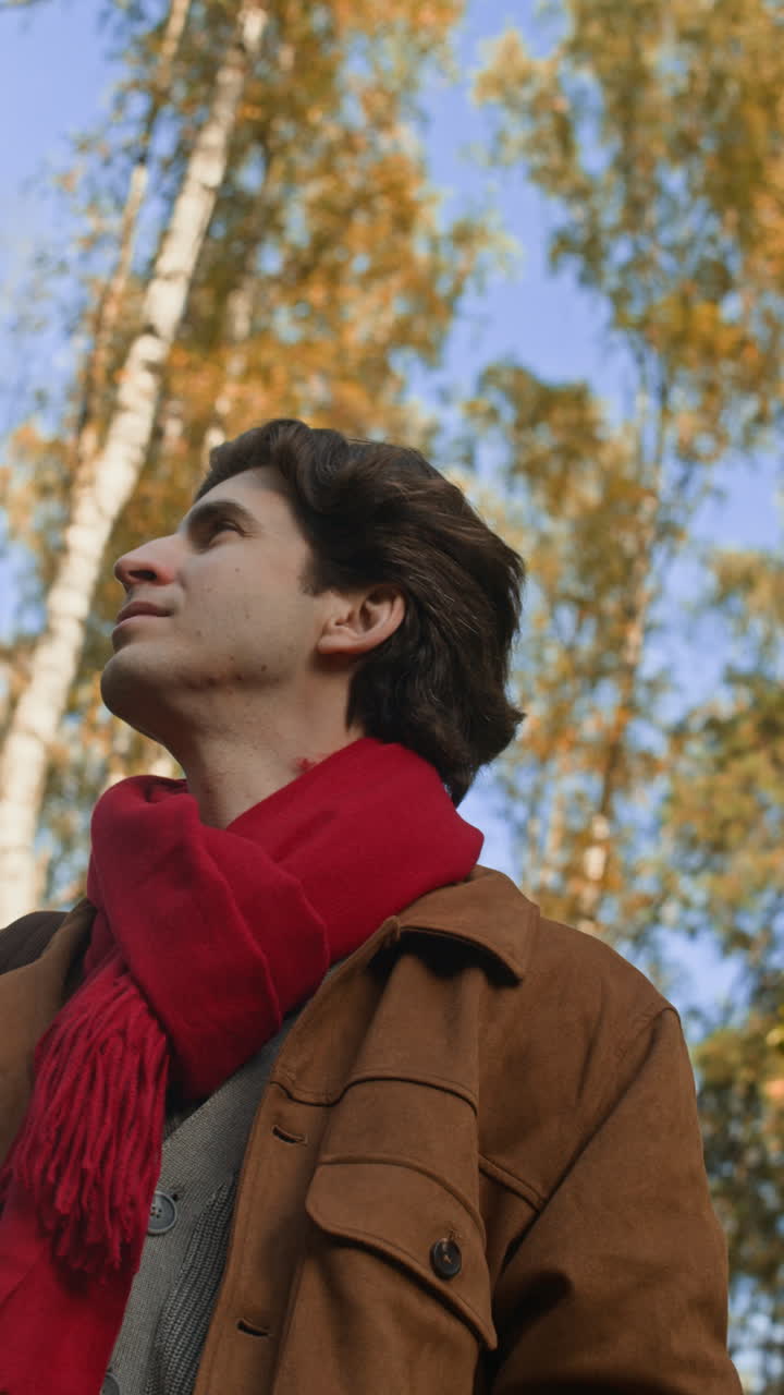 A man in a red scarf and brown jacket outdoors in the fall
