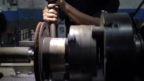 industrial mexican worker in factory operates machinery during brake disc machined on a lathe