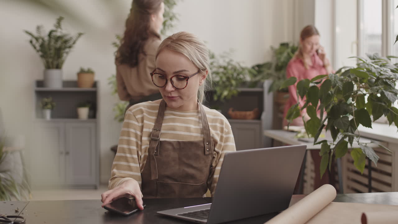 Floristin arbeitet am Laptop und Smartphone