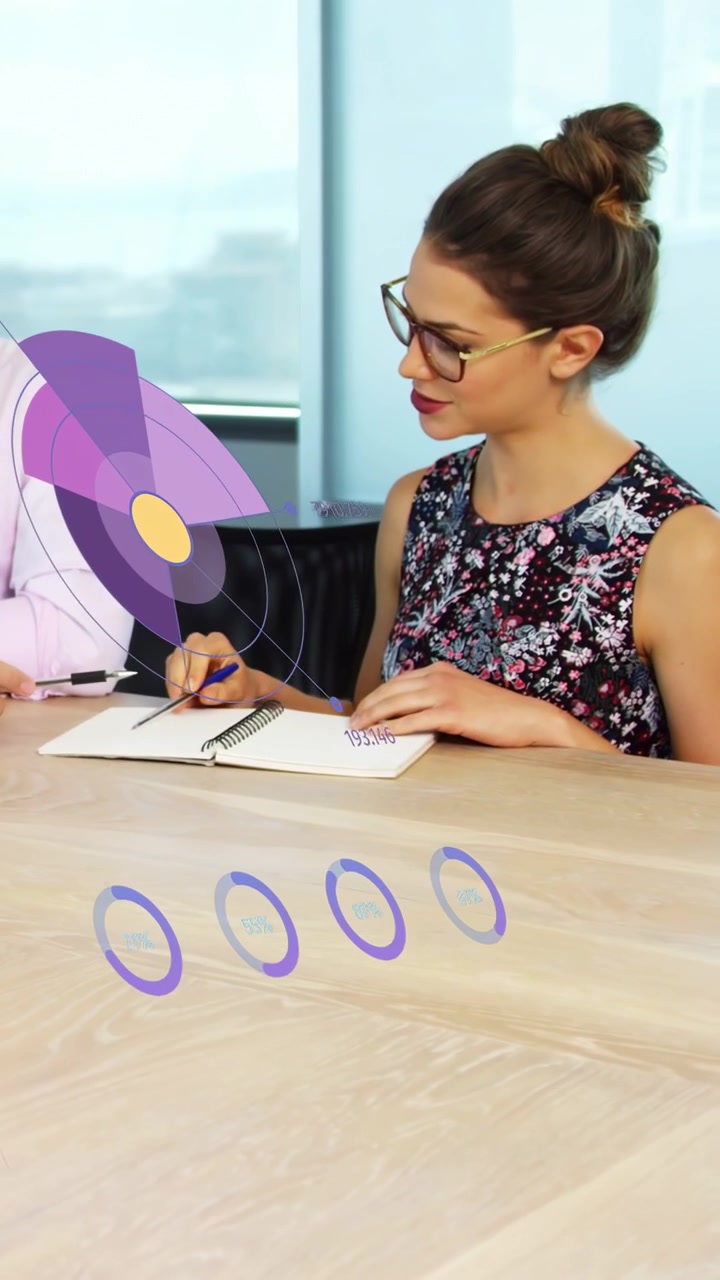 Video verticale: Uomo che punta una penna generando grafici viola mentre una donna scrive, revisionando dati aziendali.