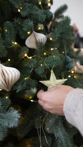 manos decorando un árbol de navidad