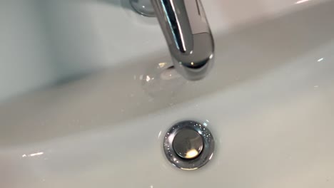 Top-view-of-broken-bathroom-tap-dripping-water-drops-into-the-sink