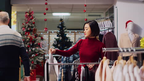 woman browsing though clothes in festive christmas clothing store, looking to buy perfect outfit for new years eve party. customer in mall fashion boutique searching for ideal attire