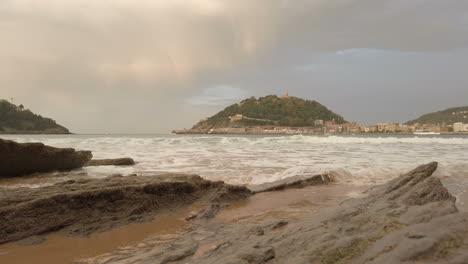 beach with rocks, mountain and city view