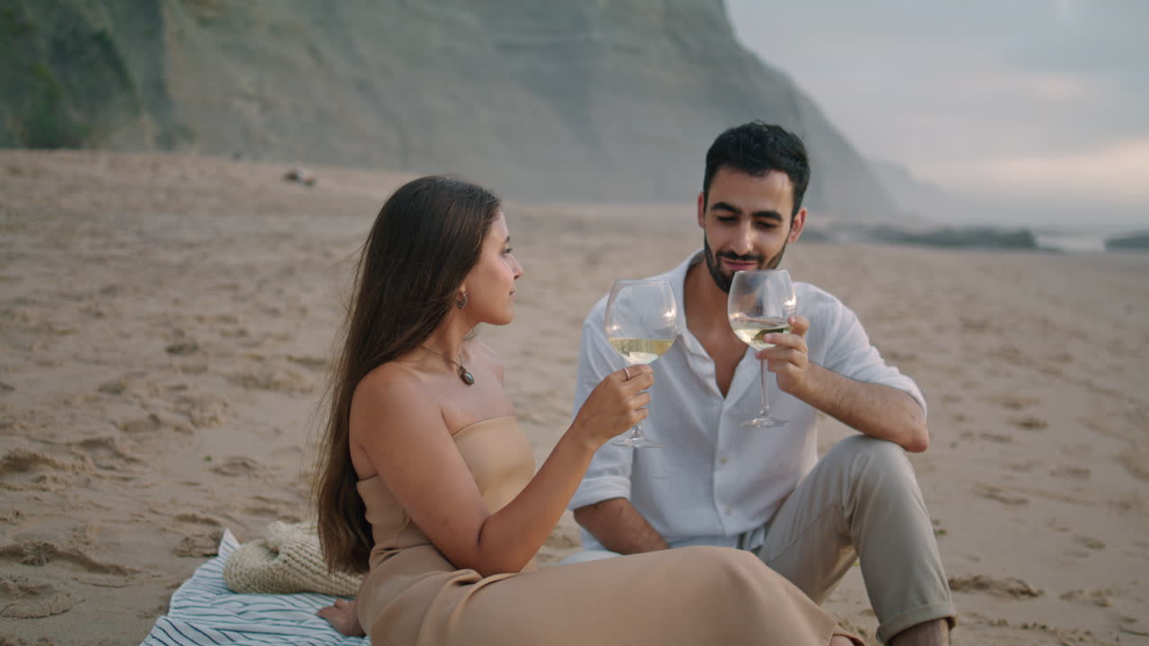 Romantisk par fejrer ferie ved kysten. Familie drikker alkohol på stranden