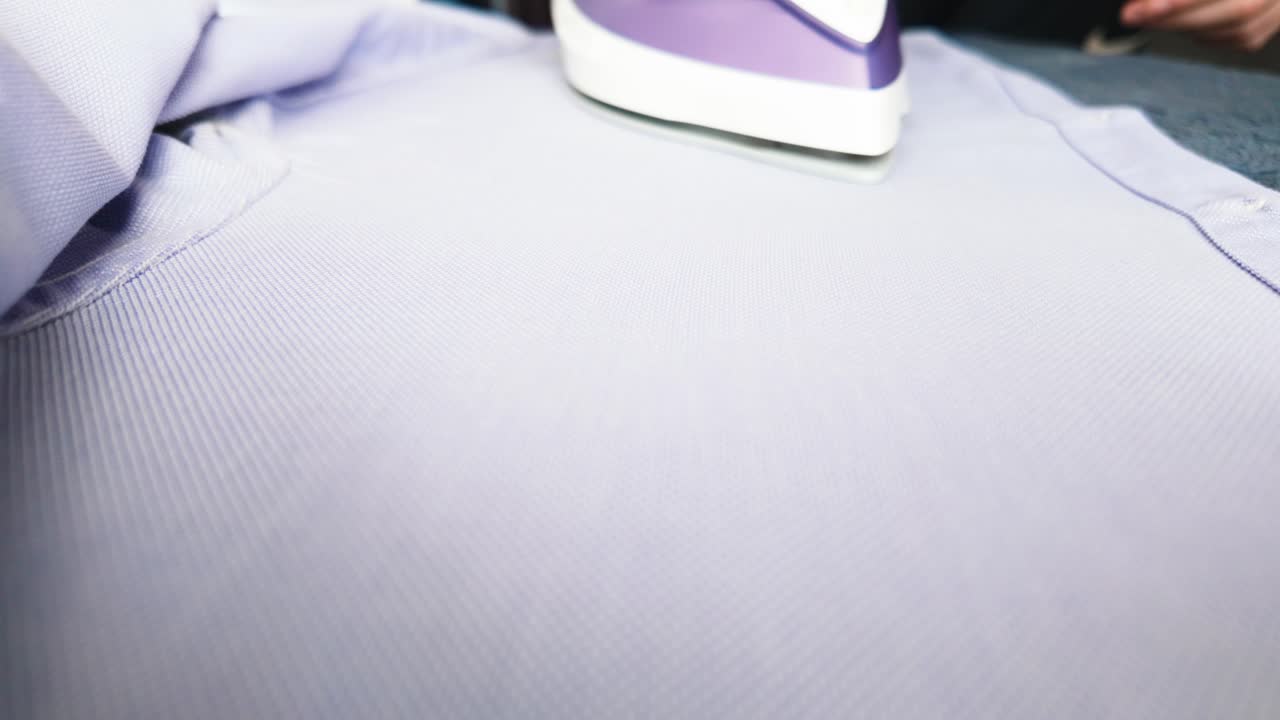 A powerful close-up of a modern iron pressing a shirt using steam