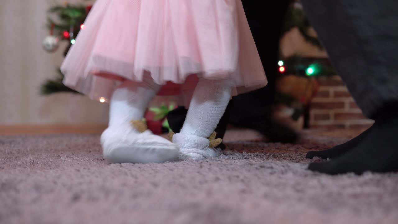 piernas de primer plano de una familia dando vueltas en un baile redondo para navidad en el árbol de navidad. abuelos y nietas celebran el año nuevo
