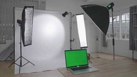 photo studio with professional equipment and green screen laptop computer display