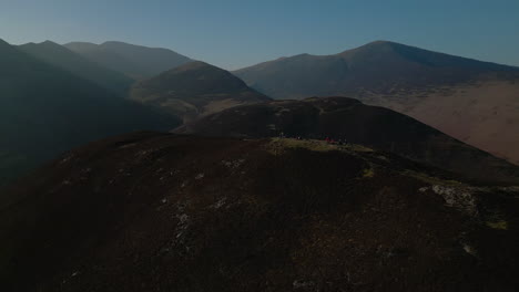 Excursionistas-En-La-Cumbre-De-La-Montaña-Con-Revelaciones-De-Montañas-Nubladas-En-Un-Día-Soleado-En-El-Distrito-Inglés-De-Los-Lagos