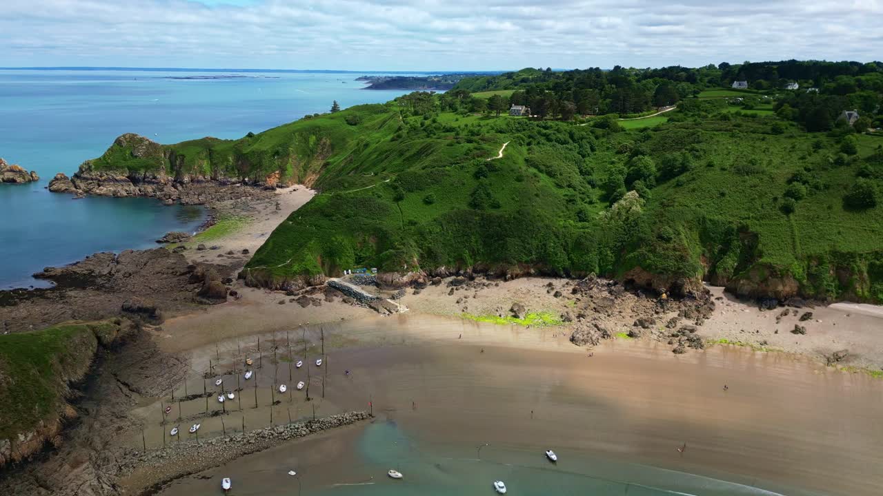 Gwin Zégal port in Brittany at low tide, boats moored to traditional wooden stakes on sandy beach, France. Aerial forward