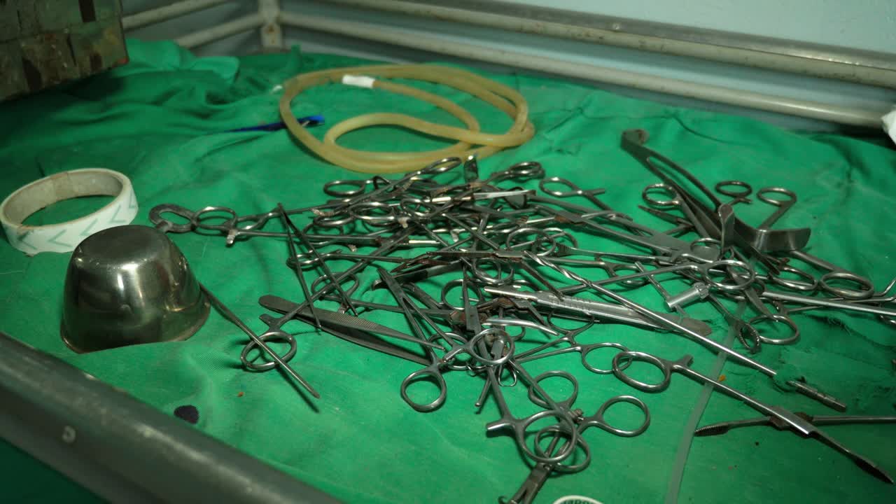Tesouras cirúrgicas de metal e pinças empilhadas sobre um tecido médico verde em um hospital obsoleto nos Camarões. Vista de ângulo alto.