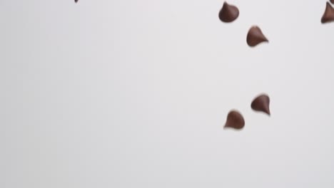 unwrapped milk chocolate hershey kiss candies raining down on white backdrop in slow motion