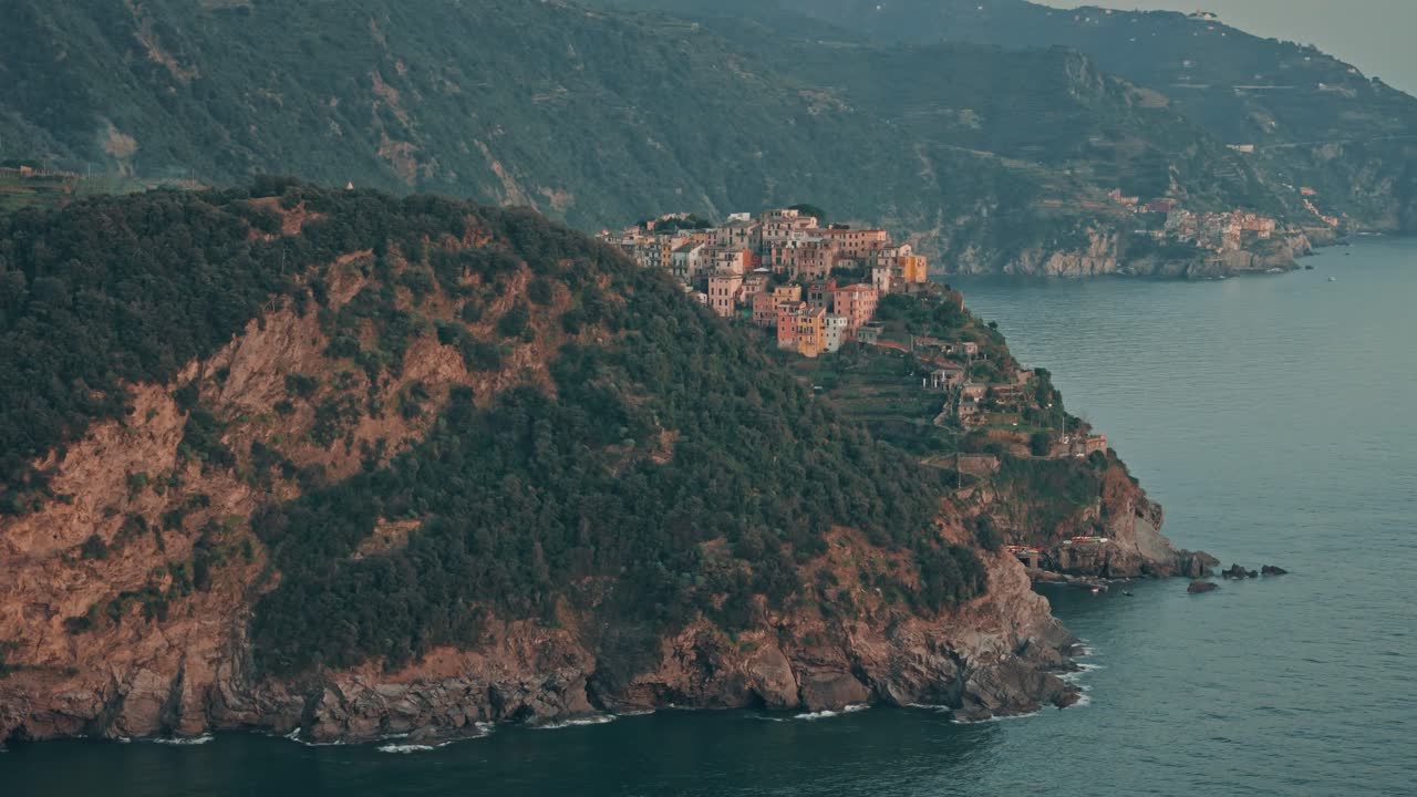 Circular orbit revealing Corniglia perched on hill at golden sunset