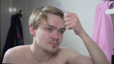 man combing his hair in the bathroom