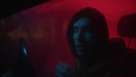 man driving at night in a car with neon lights