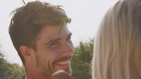 smiling couple on summer vacation sunbathing and relaxing by outdoor swimming pool