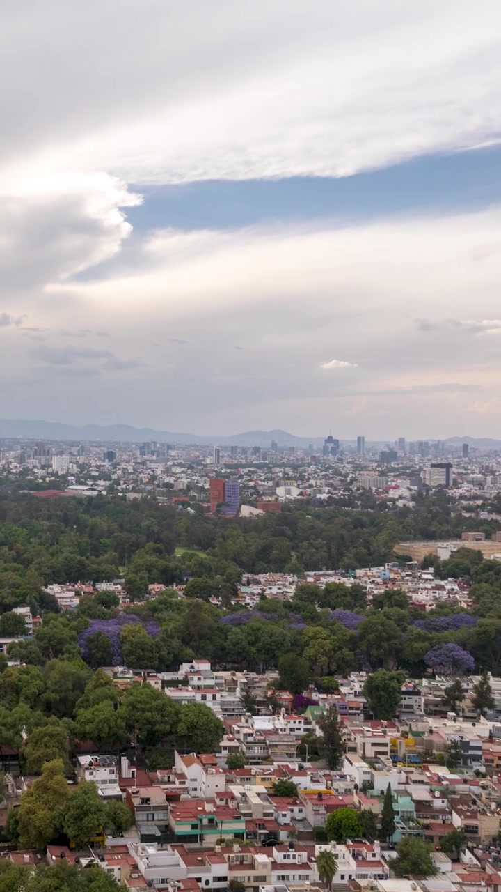 Mexico City'de Coyoacán üzerinde, golf sahası, şehir silüeti ve etkileyici bulutlarla geriye doğru uçan havadan hızlandırılmış çekim.