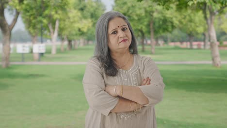 Portrait-of-Confident-Indian-old-woman-standing-crossed-hands-in-park