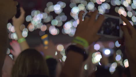 audience waving with cellphone flashlights at the concert